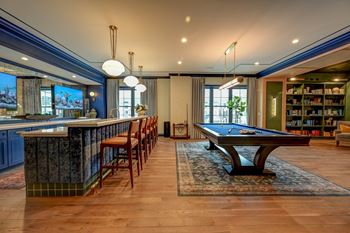 A room with a pool table and a bar area.